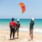 Guests learning to kiteboard on a beach